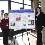 Students stand by poster presentation